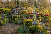 CAISSON GARDEN, SOMERSET: TERRACE WITH TABLE AND CHAIRS, EUPHORBIA, BLUE TRIPODS, TERRACOTTA CONTAINERS PLANTED WITH TULIP GAVOTA