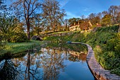 CAISSON GARDEN, SOMERSET: CAISSON HOUSE SEEN FROM THE POUND, POND WITH ENGLISH OAK BOARDWALK, DECK, EUPHORBIA PALUSTRIS, LAMIUM ORVALA, REFLECTIONS, REFLECTED