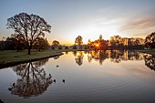 COTTESBROOKE HALL AND GARDENS, NORTHAMPTONSHIRE: SPRING, APRIL, VIEW OF PARKLAND FROM THE MITCHELL BRIDGE, SUNRISE
