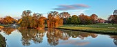 COTTESBROOKE HALL AND GARDENS, NORTHAMPTONSHIRE: SPRING, APRIL, VIEW OF PARKLAND, LAKE, BRIDGE, HALL FROM THE MITCHELL BRIDGE, SUNRISE, REFLECTED, REFLECTIONS