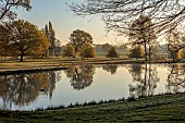 COTTESBROOKE HALL AND GARDENS, NORTHAMPTONSHIRE: SPRING, APRIL, VIEW OF PARKLAND, LAKE, FROM THE MITCHELL BRIDGE, SUNRISE