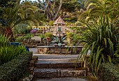 TRESCO ABBEY GARDEN, ISLES OF SCILLY: MAY, SPRING, VIEW PAST THE MEDITERRANEAN GARDEN TO THE SHELL HOUSE, AGAVE FOUNTAIN