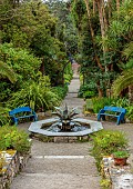 TRESCO ABBEY GARDEN, ISLES OF SCILLY: MAY, SPRING, THE MEDITERRANEAN GARDEN, BLUE WOODEN SEATS, BENCHES, COPPER AGAVE FOUNTAIN