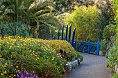 RESCO ABBEY GARDEN, TRESCO,  ISLES OF SCILLY: MAY, SPRING, GARDEN ENTRANCE, PATH, THE BLUE WOODEN BRIDGE