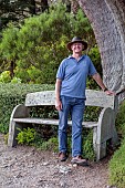 TRESCO ABBEY GARDEN, ISLES OF SCILLY: MAY, SPRING, PATH, HEAD GARDENER ANDREW LAWSON BESIDE A CUPRESSUS MACROCARPA, MONTEREY CYPRESS