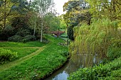 COTTESBROOKE HALL AND GARDENS, NORTHAMPTONSHIRE: SPRING, MAY: THE WILD GARDEN, STREAM, WILLOW, BRIDGE
