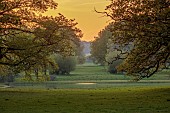 COTTESBROOKE HALL AND GARDENS, NORTHAMPTONSHIRE: SPRING, MAY: VIEW FROM THE WEST FRONT AT SUNSET, LAKE, TREES, PARKLAND
