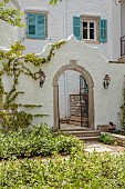 KOULOURA, CORFU, GREECE: DESIGNER PAUL BANGAY: OLD ARCHWAY, STAR JASMINE, TRACHELOSPERMUM JASMINOIDES