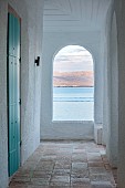 KOULOURA, CORFU, GREECE: DESIGNER PAUL BANGAY: ARCHWAY, BLUE SHUTTERS, VIEW ACROSS SEA TO ALBANIAN MOUNTAINS