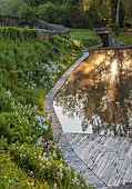 CAISSON GARDEN, SOMERSET: VIEW TO THE POUND, A DEEP POND, WATER, POOL, CANAL, DECKING, REFLECTIONS, REFLECTED, HESPERIS, EUPHORBIA PALUSTRIS, MATRONALIS VAR. ALBIFLORA