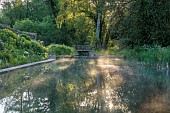 CAISSON GARDEN, SOMERSET: VIEW TO THE POUND, A DEEP POND, WATER, POOL, CANAL, DECKING, REFLECTIONS, REFLECTED, HESPERIS, EUPHORBIA PALUSTRIS, MATRONALIS VAR. ALBIFLORA