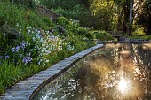 CAISSON GARDEN, SOMERSET: VIEW TO THE POUND, A DEEP POND, WATER, POOL, CANAL, DECKING, REFLECTIONS, REFLECTED, HESPERIS, IRISES, MATRONALIS VAR. ALBIFLORA