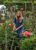 PRIORS MARSTON, WARWICKSHIRE, THE MANOR HOUSE: OWNER KATIE PICKING PEONIES IN THE WALLED KITCHEN GARDEN