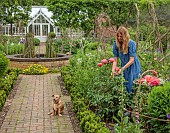 PRIORS MARSTON, WARWICKSHIRE, THE MANOR HOUSE: OWNER KATIE PICKING PEONIES IN THE WALLED KITCHEN GARDEN