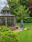 PRIORS MARSTON, WARWICKSHIRE, THE MANOR HOUSE: OWNER KATIE FEEDING CHICKENS BESIDE THE CHICKEN HOUSE