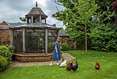 PRIORS MARSTON, WARWICKSHIRE, THE MANOR HOUSE: OWNER KATIE FEEDING CHICKENS BESIDE THE CHICKEN HOUSE