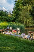 PRIORS MARSTON, WARWICKSHIRE, THE MANOR HOUSE: LONG WOODEN TABLE SET FOR DINNER ON BALCONY BESIDE THE LAKE, MAY