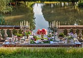 PRIORS MARSTON, WARWICKSHIRE, THE MANOR HOUSE: LONG WOODEN TABLE SET FOR DINNER ON BALCONY BESIDE THE LAKE, MAY