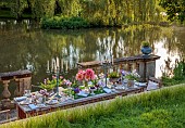 PRIORS MARSTON, WARWICKSHIRE, THE MANOR HOUSE: LONG WOODEN TABLE SET FOR DINNER ON BALCONY BESIDE THE LAKE, MAY