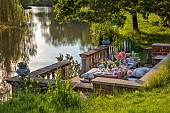 PRIORS MARSTON, WARWICKSHIRE, THE MANOR HOUSE: LONG WOODEN TABLE SET FOR DINNER ON BALCONY BESIDE THE LAKE, MAY