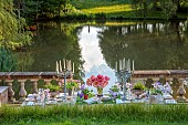 PRIORS MARSTON, WARWICKSHIRE, THE MANOR HOUSE: LONG WOODEN TABLE SET FOR DINNER ON BALCONY BESIDE THE LAKE, MAY