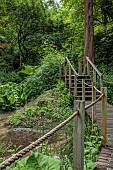 THE MANOR HOUSE, BLEDLOW, BUCKINGHAMSHIRE: THE LYDE WATER GARDEN FORMED OUT OF OLD CRESS BEDS, WOODEN WALKWAY ACROSS STREAM