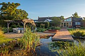TYTHE BARN, OXFORDSHIRE, DESIGNER SARAH NAYBOUR: JUNE, WILDLIFE POND, DECKING, LAWN, POOL, WATER, WOODEN JACUZZI. OAK PERGOLA