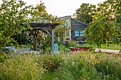 TYTHE BARN, OXFORDSHIRE, DESIGNER SARAH NAYBOUR: JUNE, WILDFLOWERS, DECKING, LAWN, WOODEN JACUZZI. OAK PERGOLA