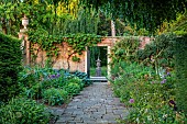 COTTESBROOKE HALL AND GARDENS, NORTHAMPTONSHIRE: JUNE, THE TERRACE, DOUBLE HERBACEOUS BORDERS, PATH, ALLIUMS, HOSTA SIEBOLDIANA VAR. ELEGANS, WALL, GATE, URN