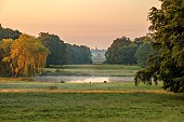 COTTESBROOKE HALL AND GARDENS, NORTHAMPTONSHIRE: VIEW ACROSS SOUTH LAWN TO BRIXWORTH CHURCH, WATER, DAWN, SUNRISE, BORROWED LANDSCAPE