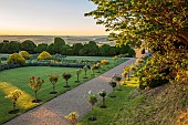 ROCKINGHAM CASTLE, NORTHAMPTONSHIRE: JUNE, PATH WITH STANDARD DAVID AUSTIN ROSES, THE CROSS GARDEN DESIGNED BY JOHN CODRINGTON, LAWN, ELEPHANT YEW CLOUD HEDGE, HEDGES