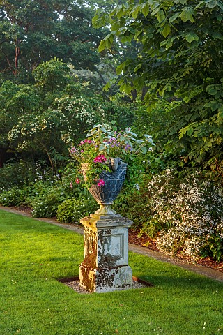 COTTESBROOKE_HALL_AND_GARDENS_NORTHAMPTONSHIRE_LAWN_STONE_CONTAINER_WITH_PELARGONIUM_HAPPY_FACE_MAGE