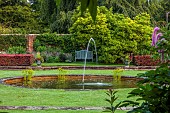 COTTESBROOKE HALL AND GARDENS, NORTHAMPTONSHIRE: THE POOL GARDEN, FOUNTAIN, POND, WATER, LAWN,  COPPER BEECH HEDGE, WALL, WALLED, WOODEN BENCH