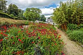 JUNE BLAKES GARDEN, IRELAND: JULY, RED BORDER, MONARDA JACOB CLINE, CROCOSMIA, HOT COLOURS, PATH