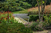 JUNE BLAKES GARDEN, IRELAND: BLACK REFLECTING POOL, RUSTED STEEL EDGING, PEBBLES, SEAT, BENCH