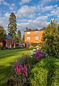 MORTON HALL GARDENS, WORCESTERSHIRE: THE WEST GARDEN, SUNSET, EVENING, HALL, LAWN, BORDER, LYTHRUM VIRGATUM DROPMORE PURPLE, HYDRANGEA INCREDIBALL