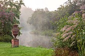 JOHN MASSEY GARDEN, ASHWOOD NURSERIES, WORCESTERSHIRE: SEPTEMBER, VIEW TO CANAL AND TERRACOTTA CONTAINER, MIST, MISTY, FOG