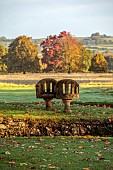 LLANOVER GARDEN, MONMOUTHSHIRE: OCTOBER, FALL, AUTUMN, STONE LOVE SEAT LOOKING OVER PARKLAND, LANDSCAPE