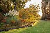 LLANOVER GARDEN, MONMOUTHSHIRE: AUTUMN COLOUR, FALL, OCTOBER, STREAM, LOWER ARBORETUM, TREES, PAMPAS GRASS, RHUS