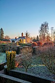 THE LASKETT GARDEN, HEREFORDSHIRE: WINTER, FROST, JANUARY, VIEW FROM THE BELVEDERE TO THE HOUSE, CLIPPED TOPIARY YEW, HEDGES, HEDGING, SUNRISE