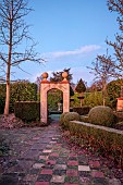 THE LASKETT GARDEN, HEREFORDSHIRE: WINTER, FROST, JANUARY, PATH, ARCH, GATE INTO THE SILVER JUBILEE GARDEN, SUNDIAL, CLIPPED TOPIARY HEDGES, HEDGING
