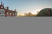 HELMINGHAM HALL GARDENS, SUFFOLK: WINTER, FROST, JANUARY, THE HALL AND MOAT WITH CLIPPED TOPIARY YEW