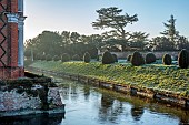 HELMINGHAM HALL GARDENS, SUFFOLK: WINTER, FROST, JANUARY, MOAT, BANK, CLIPPED TOPIARY YEW