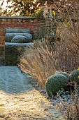HELMINGHAM HALL GARDENS, SUFFOLK: WINTER, FROST, JANUARY, THE WALLED GARDEN, CLIPPED TOPIARY YEWS, PATH, WALLS, GRASSES, CLIPPED BOX BALLS