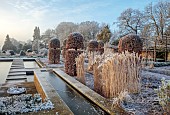 BROUGHTON GRANGE GARDENS, OXFORDSHIRE: WINTER, FROST, JANUARY, RILL, WATER, POOL, POND, STEPPING STONES, GRASSES, FAGUS SYLVATICA, CLIPPED, TOPIARY, BEECH