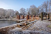 BROUGHTON GRANGE GARDENS, OXFORDSHIRE: WINTER, FROST, JANUARY, BEECH HEDGES, HEDGING, CLIPPED, TOPIARY, FAGUS SYLVATICA, POOL, POND, WATER, STEPPING STONES