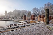 BROUGHTON GRANGE GARDENS, OXFORDSHIRE: WINTER, FROST, JANUARY, BEECH HEDGES, HEDGING, CLIPPED, TOPIARY, FAGUS SYLVATICA, POOL, POND, WATER, STEPPING STONES