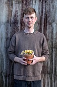 DAVID CARVER CROCUS COLLECTION DEVON: FEBRUARY, DAVID CARVER HOLDS TERRACOTTA CONTAINER WITH FLOWERS, BLOOMS OF CROCUS MIDAS TOUCH, BULBS