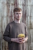 DAVID CARVER CROCUS COLLECTION DEVON: FEBRUARY, DAVID CARVER HOLDS TERRACOTTA CONTAINER WITH FLOWERS, BLOOMS OF CROCUS MIDAS TOUCH, BULBS