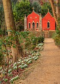 PAINSWICK ROCOCO GARDEN, GLOUCESTERSHIRE: THE RED HOUSE WITH BANK OF SNOWDROPS, GARDEN BUILDING, FEBRUARY, DRIFTS, PATHS